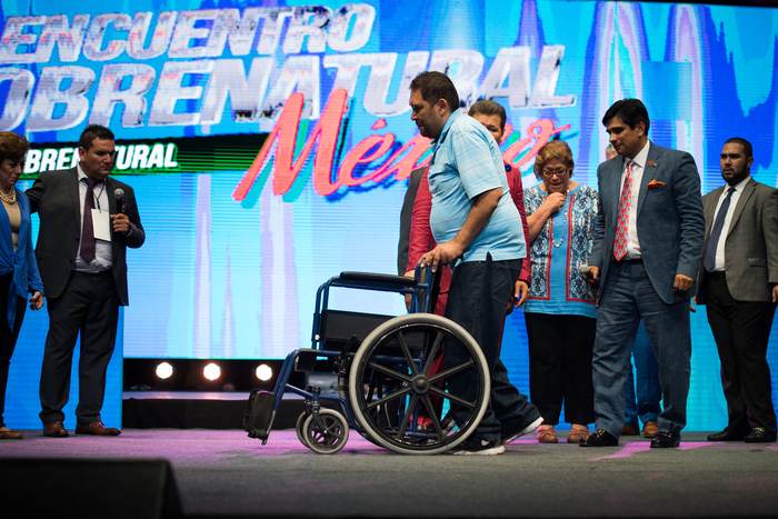 A man standing beside the wheelchair he arrived in